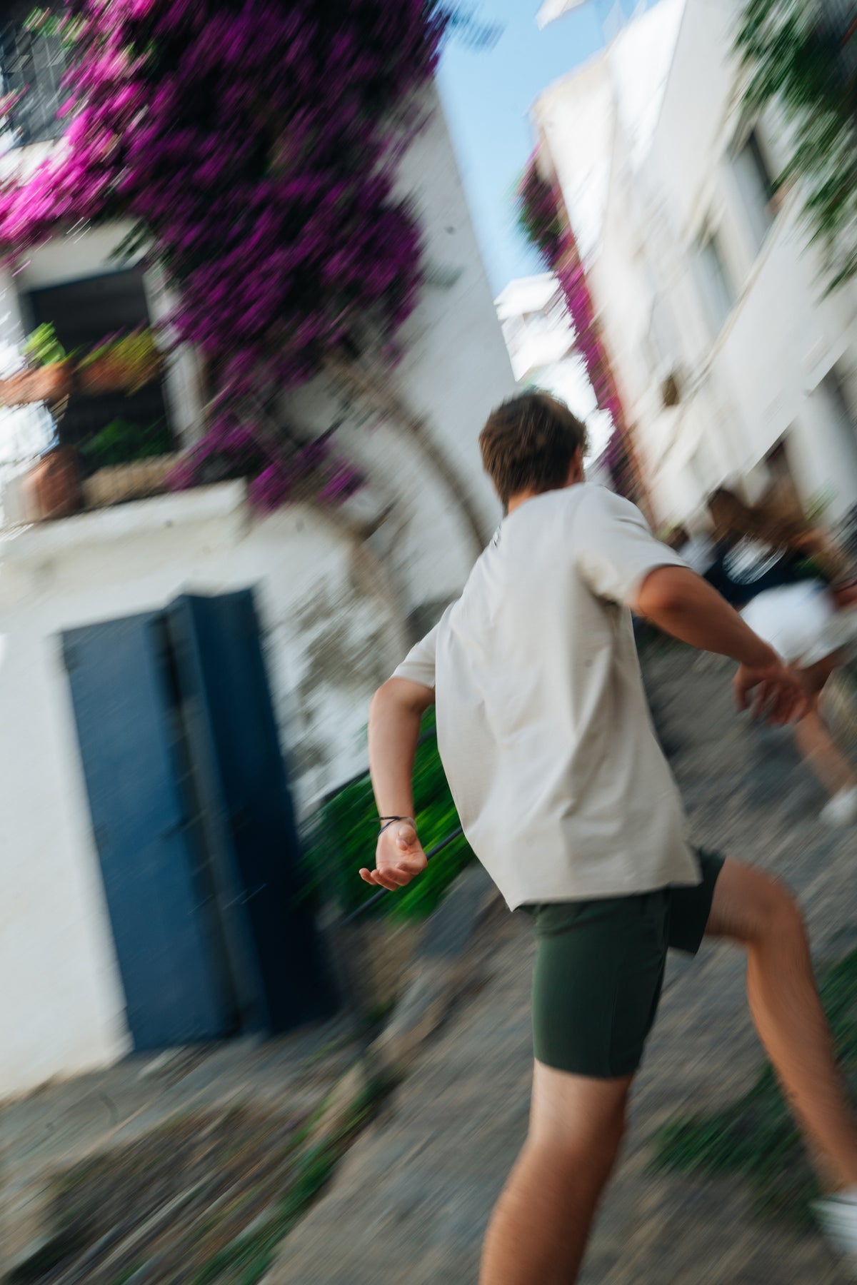 Noi corrent per un carrer de Cadaqués amb buguenvíl·lees